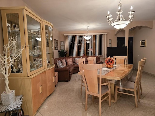 dining room with light tile patterned flooring, arched walkways, and a chandelier