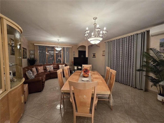 tiled dining room with a wall mounted air conditioner, a chandelier, and arched walkways