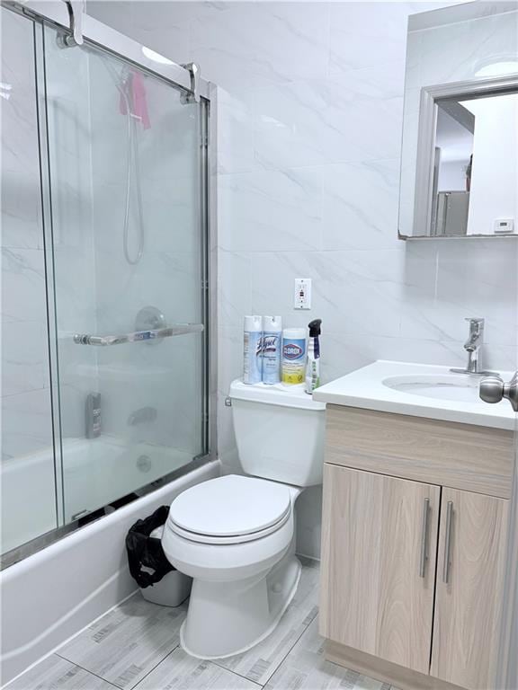 2349 W 12th St, Brooklyn, NY 11223 - full bath with tile walls, vanity, bath / shower combo with glass door, toilet, and decorative backsplash