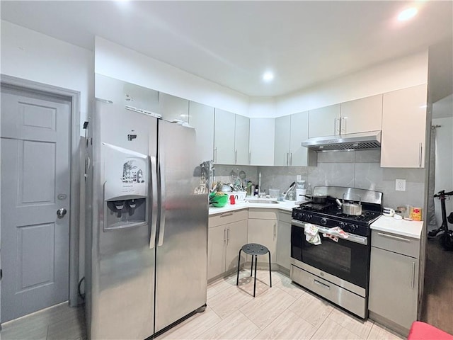 2349 W 12th St, Brooklyn, NY 11223 - kitchen with stainless steel appliances, under cabinet range hood, light countertops, backsplash, and gray cabinetry