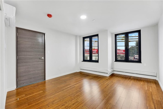 empty room featuring hardwood / wood-style flooring, baseboards, recessed lighting, and baseboard heating