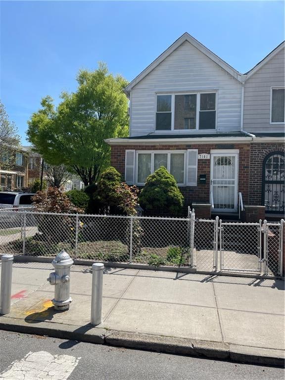 view of front of property featuring brick siding, a fenced front yard, and a gate