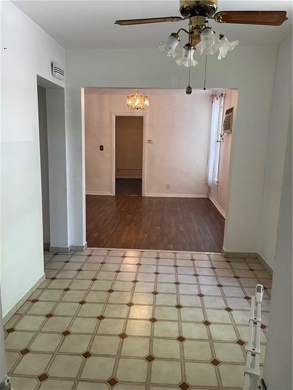unfurnished room with ceiling fan, a chandelier, baseboards, and wood finished floors