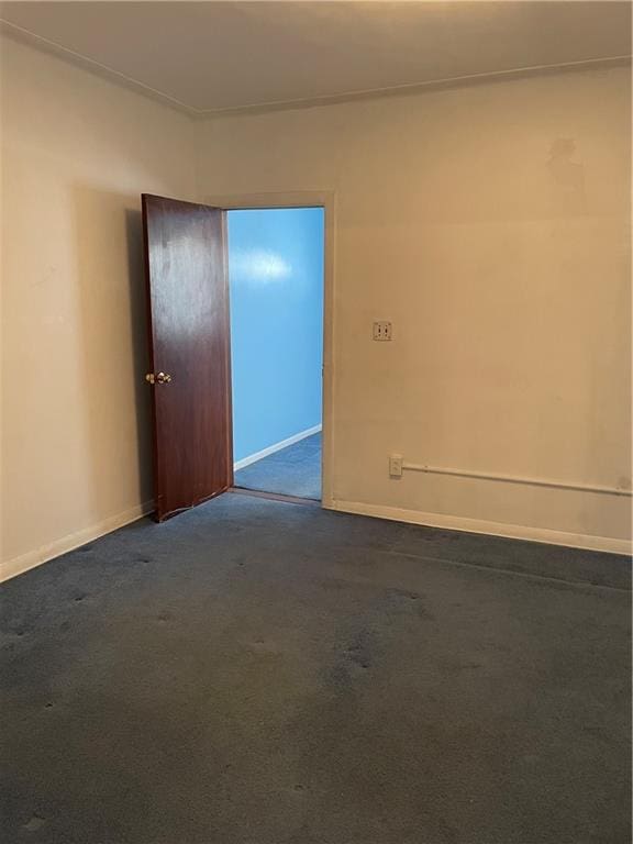 spare room with dark carpet and baseboards