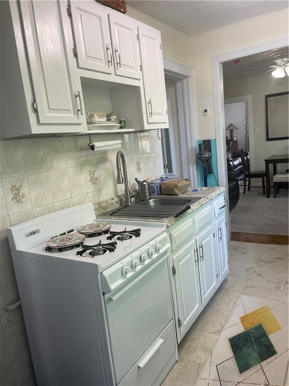 kitchen featuring white range with gas cooktop, a sink, light countertops, light marble finish floors, and crown molding