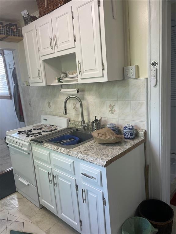 kitchen with white gas range, white cabinetry, backsplash, a sink, and open shelves