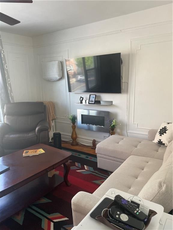 living room with ceiling fan and a glass covered fireplace