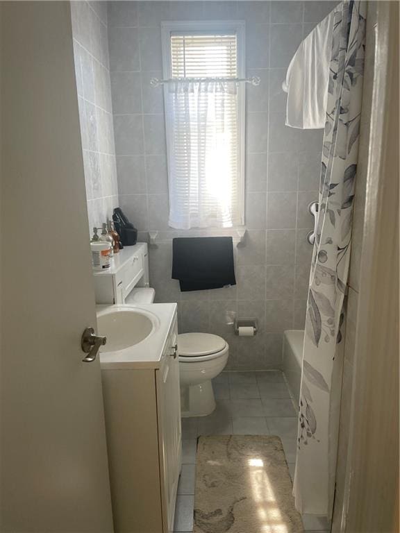 full bath featuring tile walls, tile patterned flooring, vanity, toilet, and shower / bath combo with shower curtain