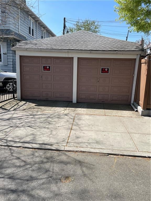 garage with fence and concrete driveway
