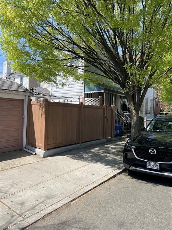 view of side of home featuring fence and a garage
