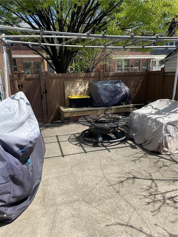 view of patio with fence, a gate, and a grill