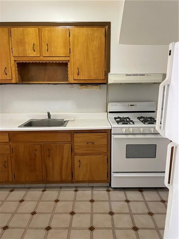 kitchen with white range with gas cooktop, a sink, under cabinet range hood, and light floors