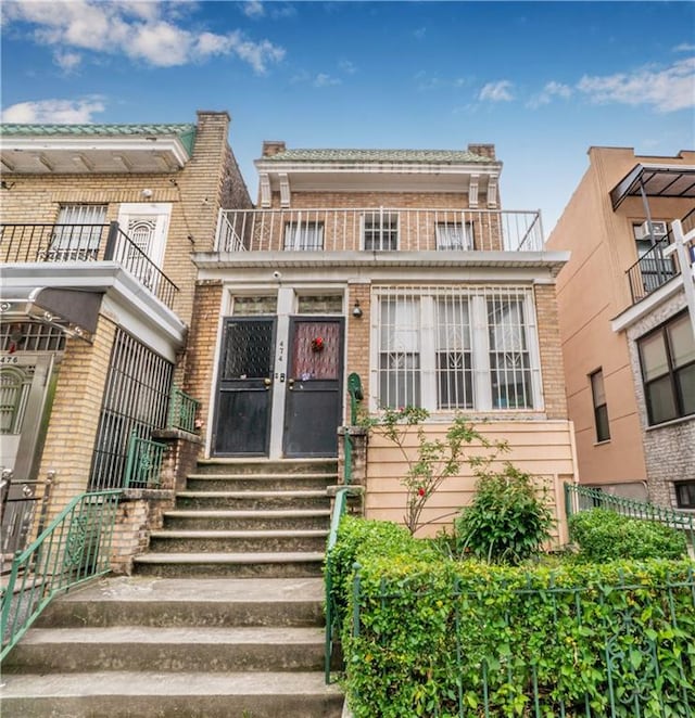 view of front of house featuring entry steps, a balcony, and brick siding