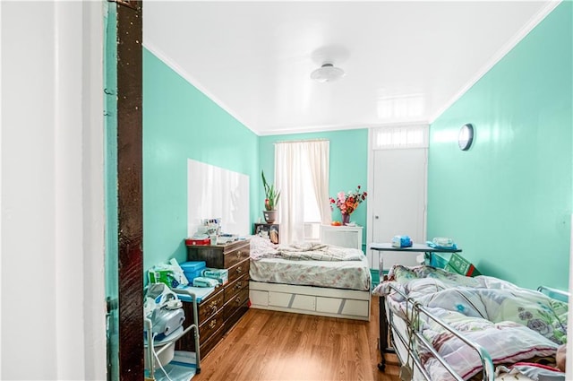bedroom with ornamental molding and wood finished floors