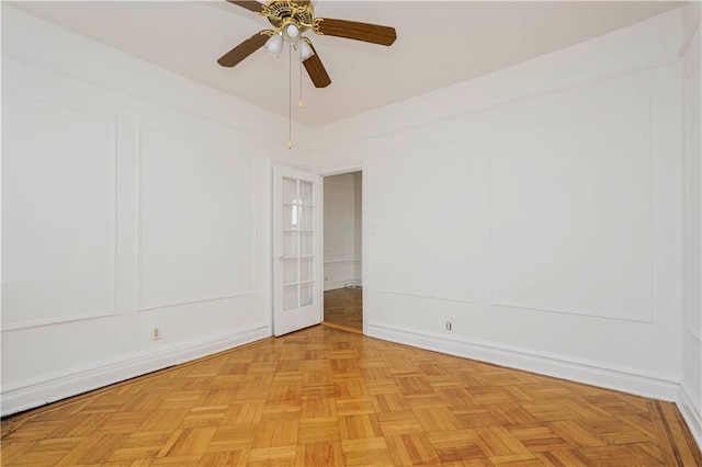 unfurnished room with a decorative wall, ceiling fan, and baseboards