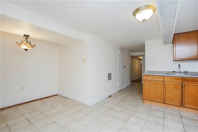 kitchen with a sink, light countertops, brown cabinetry, and baseboards
