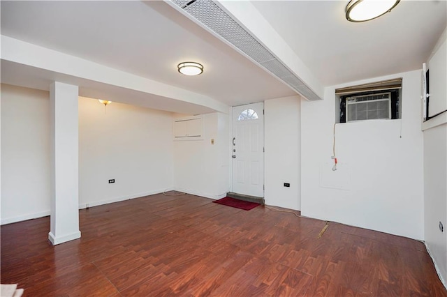 finished below grade area with wood finished floors, a wall mounted air conditioner, and baseboards