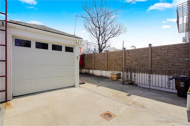 garage with concrete driveway and fence
