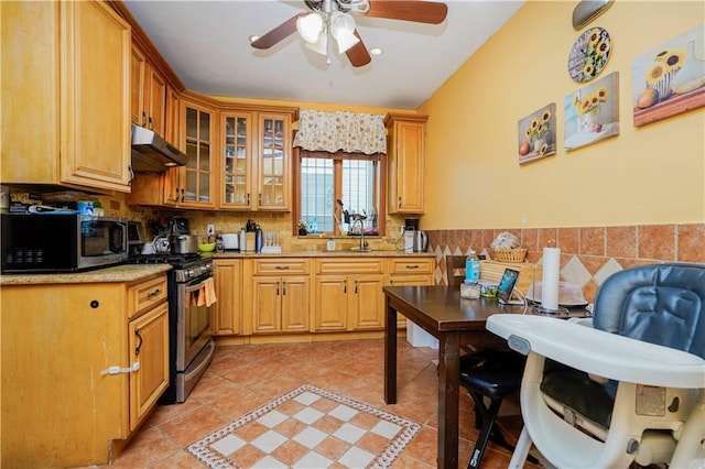 kitchen featuring appliances with stainless steel finishes, under cabinet range hood, a ceiling fan, light tile patterned floors, and glass insert cabinets