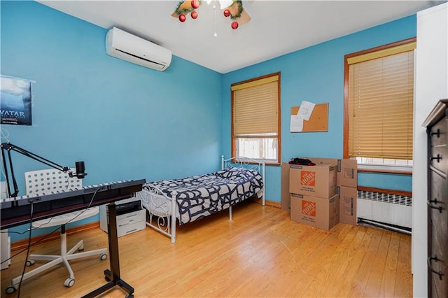 bedroom with radiator, a wall mounted AC, and hardwood / wood-style flooring