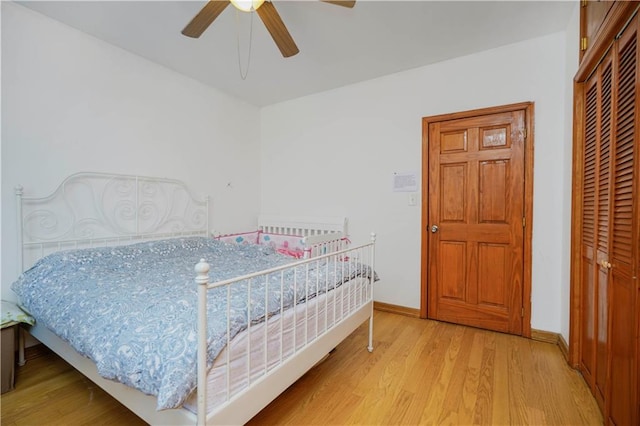 bedroom with wood finished floors, a closet, baseboards, and a ceiling fan