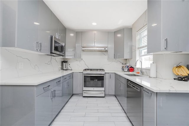 kitchen with gray cabinetry, stainless steel appliances, and a sink