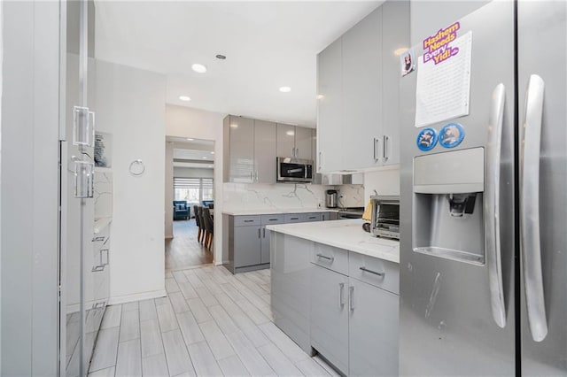 kitchen featuring appliances with stainless steel finishes, gray cabinets, modern cabinets, recessed lighting, and tasteful backsplash