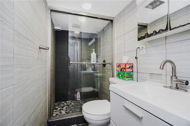 bathroom featuring toilet, tile walls, a stall shower, and vanity