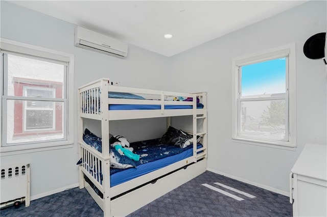 bedroom with a wall mounted air conditioner, radiator, baseboards, and carpet flooring