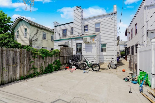rear view of house with fence, a chimney, and a patio