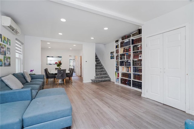living room with a wall mounted AC, wood finished floors, stairs, and recessed lighting