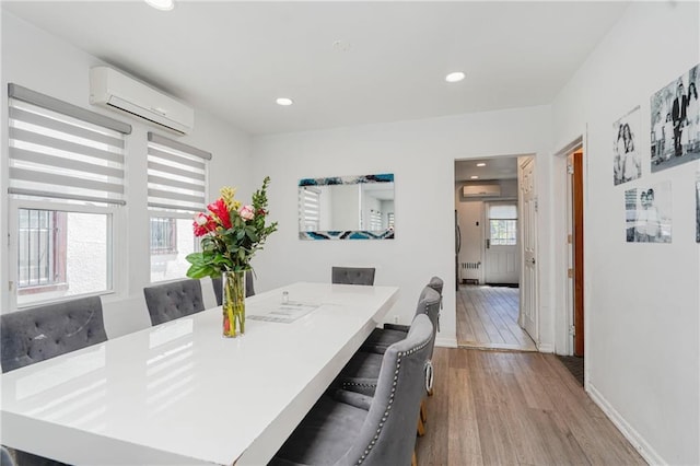 dining area with a wall unit AC, an AC wall unit, wood finished floors, baseboards, and recessed lighting