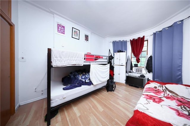 bedroom with crown molding, wood finished floors, baseboards, and radiator heating unit