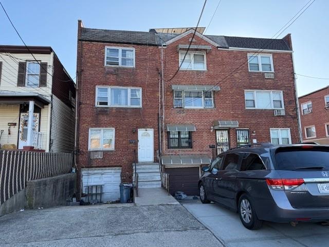 townhome / multi-family property featuring driveway, brick siding, an attached garage, and entry steps