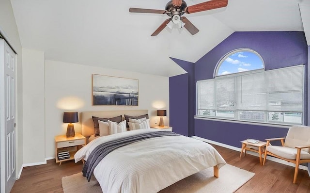 bedroom featuring lofted ceiling, wood finished floors, a closet, a ceiling fan, and baseboards