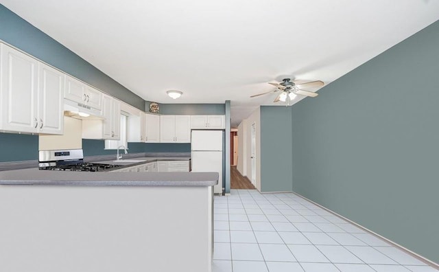 kitchen with freestanding refrigerator, under cabinet range hood, stainless steel gas stove, a ceiling fan, and white cabinetry