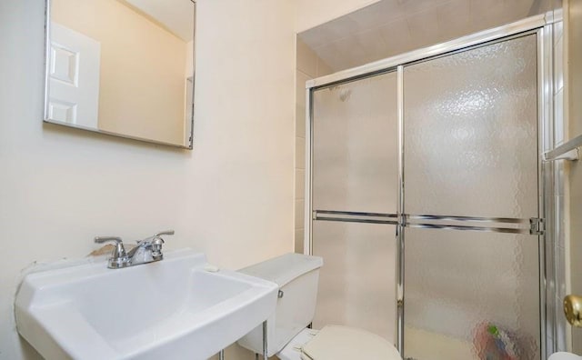 bathroom featuring a sink, a stall shower, and toilet