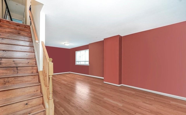 spare room featuring wood finished floors, baseboards, and stairs