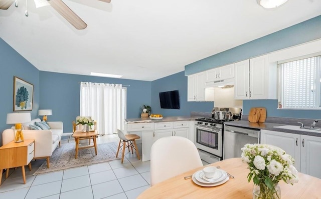 kitchen featuring stainless steel appliances, white cabinetry, light tile patterned floors, under cabinet range hood, and ceiling fan