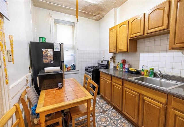 1777 Union St, Brooklyn, NY 11213 - kitchen with stainless steel gas stove, a sink, dark countertops, brown cabinetry, and tile walls