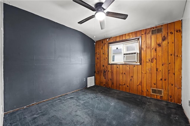 carpeted empty room featuring ceiling fan, wooden walls, lofted ceiling, and cooling unit