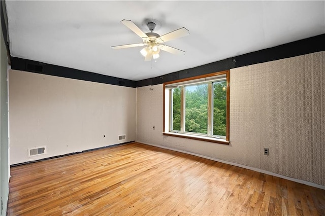 unfurnished room with light wood-style flooring, a ceiling fan, and baseboards