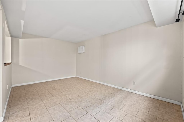 empty room featuring baseboards, light tile patterned floors, and lofted ceiling