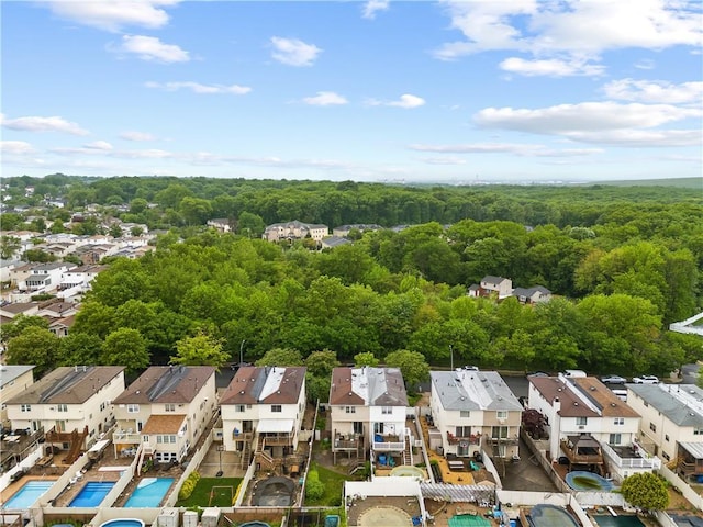 aerial perspective of suburban area featuring a forest and a pool
