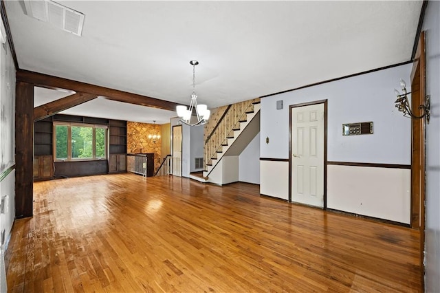 unfurnished living room featuring a chandelier, wood finished floors, stairs, and beam ceiling