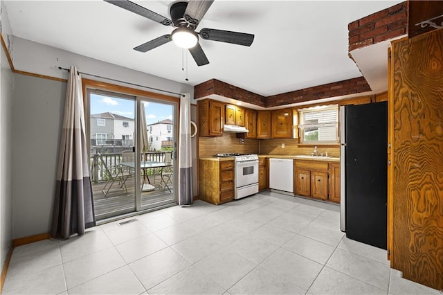 kitchen featuring white appliances, under cabinet range hood, light countertops, ceiling fan, and a sink