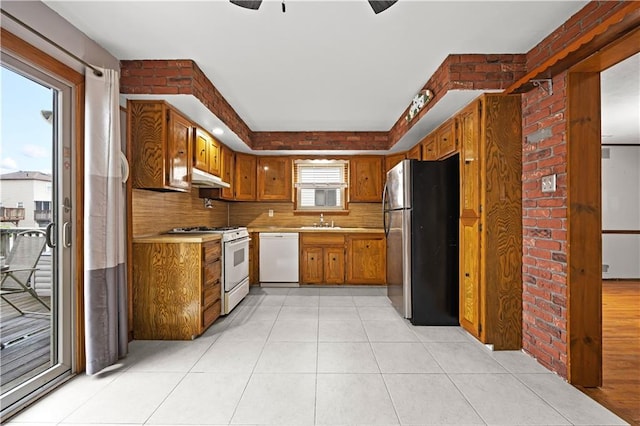 kitchen featuring white appliances, under cabinet range hood, a sink, brown cabinetry, and ceiling fan