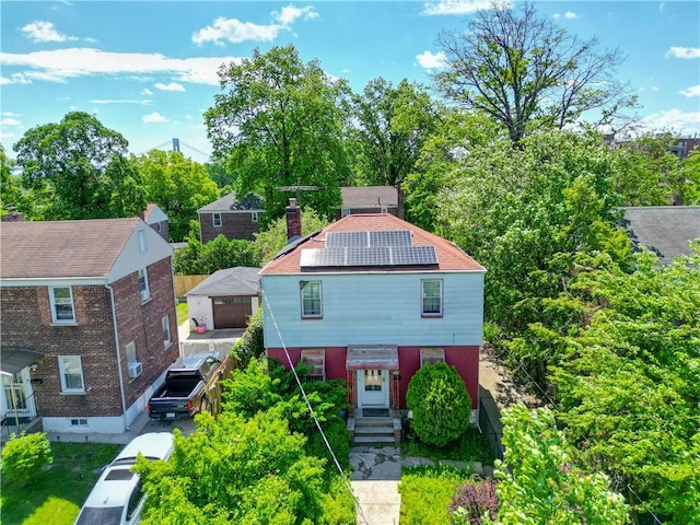 view of front facade with solar panels, brick siding, and a chimney