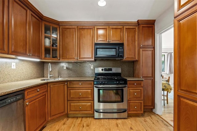 kitchen with black microwave, stainless steel range with gas cooktop, dishwashing machine, a sink, and brown cabinets