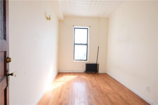 642 56th St, Brooklyn, NY 11220 - empty room with radiator, light wood-style floors, and baseboards